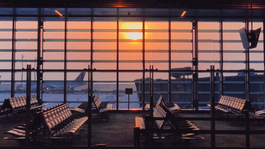 Evening view at the airport with standing airplanes and empty seats.