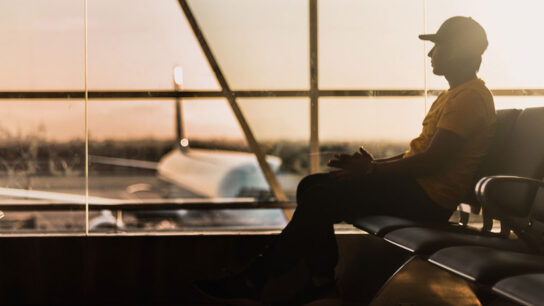 Man sitting on the chair and looking towards the airoplane.