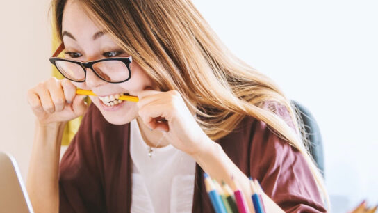 Angry female student biting pencil