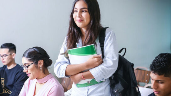 Female student holding book and smiling