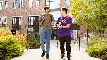 students walking out of campus talking surrounded by greenery