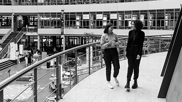 Black and white image of people on campus walkway