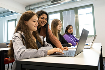 students learning on campus with assistance from teacher