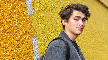 student leaning against vibrant wall