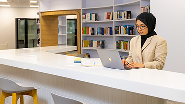 student using laptop in campus library