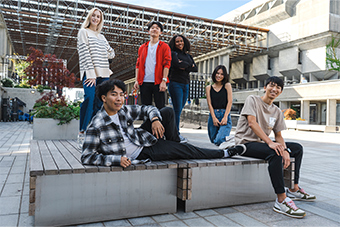 group of students posing and smiling on campus square