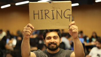 A man standing and holding hiring banner