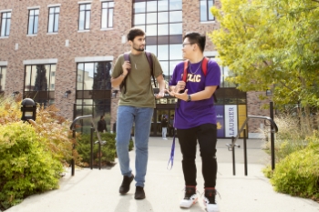 Two students walking and talking at campus entrance